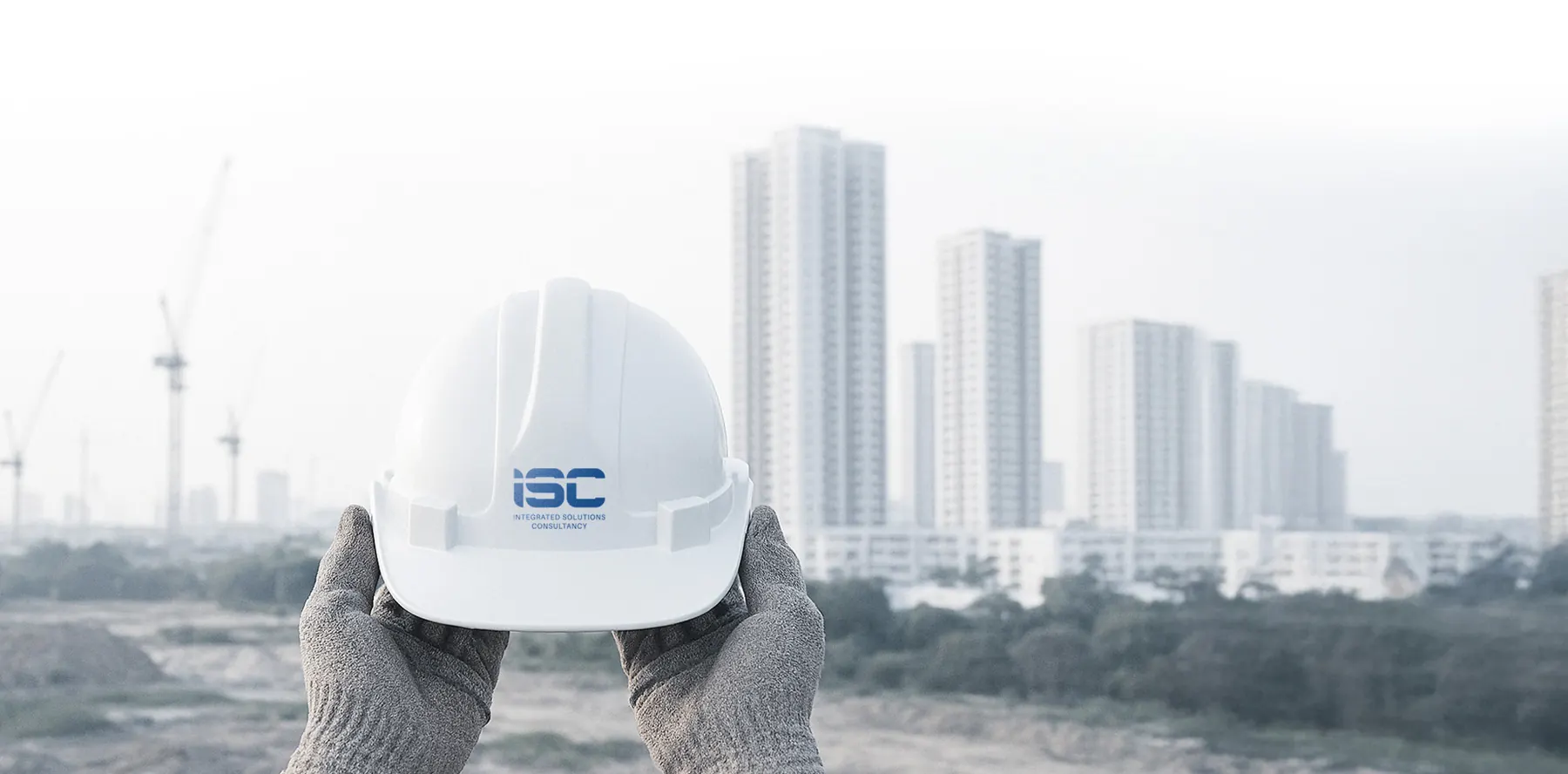 An ISC-branded safety helmet held up in front of a city skyline under construction